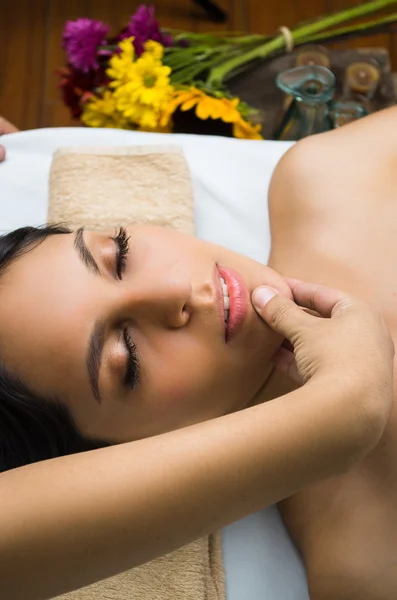 Modelo morena hispânica recebendo tratamento de spa de massagem, mãos trabalhando em massagear as mulheres cabeça e rosto com os olhos fechados — Fotografia de Stock