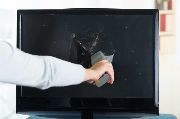 Womans hand removing remote control from broken computer screen — 图库照片