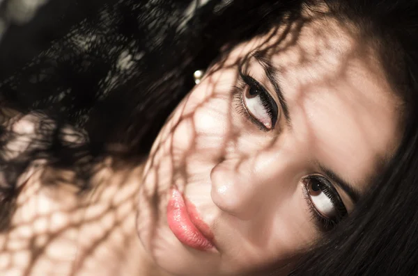 Cabeza morena modelo utilizando sombras estampadas como efecto artístico en la cara mientras posando —  Fotos de Stock