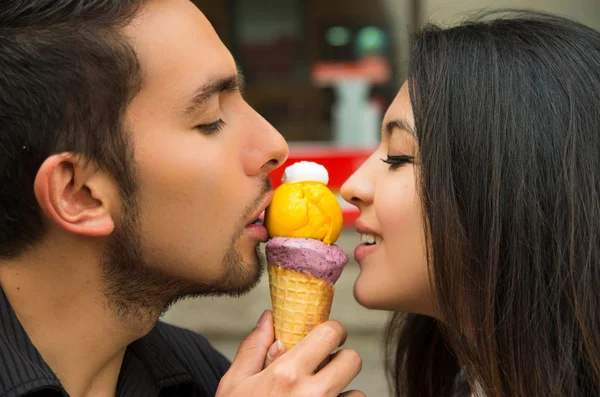 Linda pareja hispana compartiendo cono de helado y disfrutando de la compañía de los demás en el ambiente al aire libre — Foto de Stock