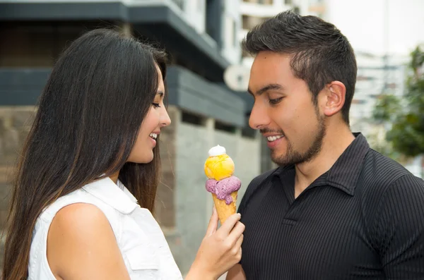 Linda pareja hispana compartiendo cono de helado y disfrutando de la compañía de los demás en el ambiente al aire libre — Foto de Stock