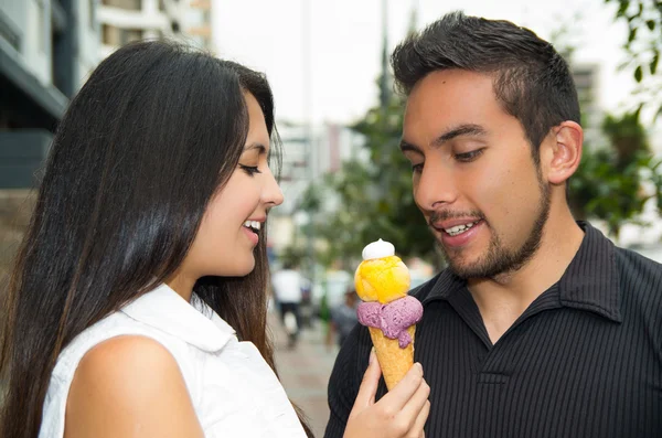 Linda pareja hispana compartiendo cono de helado y disfrutando de la compañía de los demás en el ambiente al aire libre — Foto de Stock