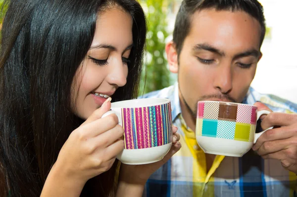 Латиноамериканская милая пара наслаждается кофе во время уютного свидания на открытом воздухе и зеленый фон растительности — стоковое фото