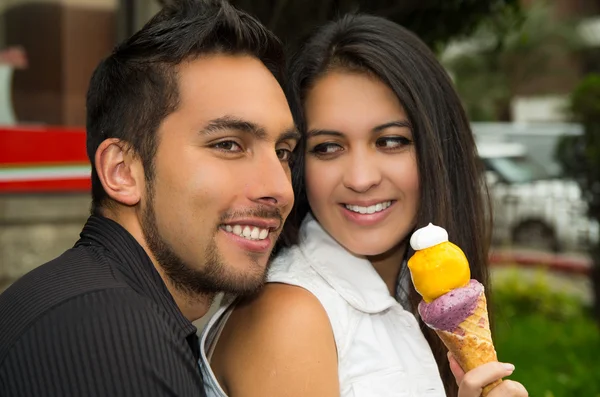 Linda pareja hispana compartiendo cono de helado y disfrutando de la compañía de los demás en el ambiente al aire libre — Foto de Stock