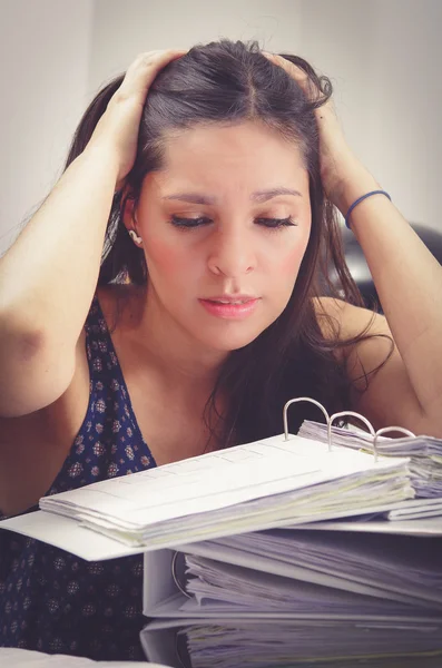 Ispanico bruna ufficio donna lavoro seduta a scrivania con archivio di file di carta aperto e cercando stanco — Foto Stock