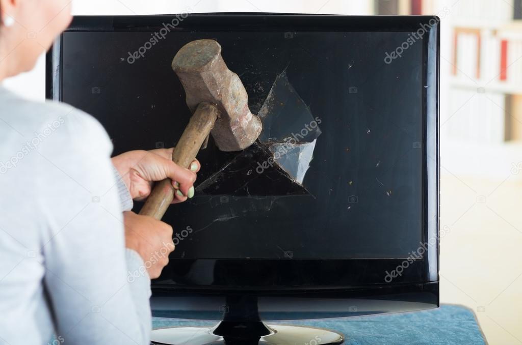 Female holding hammer smashing it into computer screen