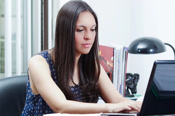 Mulher escritório morena hispânica sentado à mesa e trabalhando no computador com atitude positiva sorrindo — Fotografia de Stock