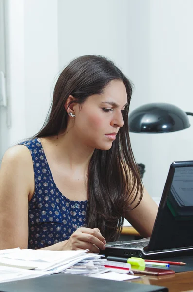 Hispanic brunette office woman sitting by desk and working on computer with positive attitude smiling — Stock Photo, Image