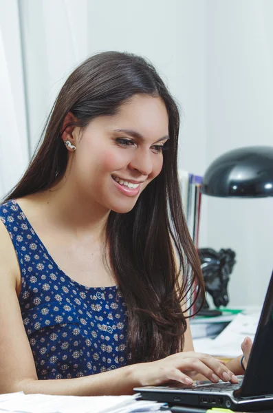 Mulher escritório morena hispânica sentado à mesa e trabalhando no computador com atitude positiva sorrindo — Fotografia de Stock