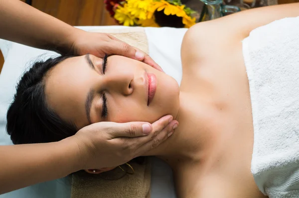 Modelo morena hispana recibiendo tratamiento de spa de masaje, manos alrededor de la cabeza de las mujeres con los ojos cerrados — Foto de Stock