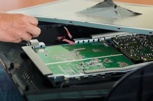 Hands working with electronic circuit board from broken computer screen using small screwdriver — 图库照片