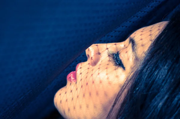 Headshot brunette model using patterned shadows as artistic effect on face while posing — ストック写真