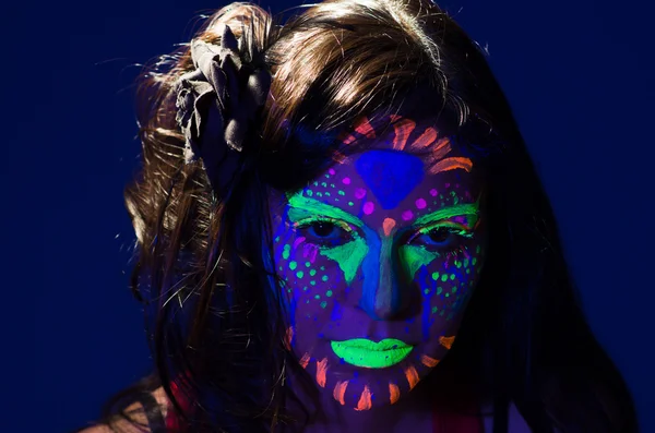 Frau mit Kopfschuss, die einen fantastischen Schein in dunkler Gesichtsfarbe trägt, blau mit anderen Neonfarben und obskuren abstrakten Hintergrund, vor der Kamera — Stockfoto