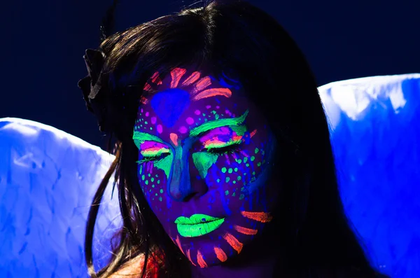 Mujer en la cabeza con un brillo impresionante en pintura facial oscura, azul basado en otros colores de neón y oscuro fondo abstracto, frente a la cámara — Foto de Stock