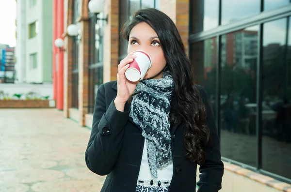 Stijlvolle vrouw dragen donkere vacht en witte zwarte sjaal in stedelijk milieu drinken van koffiemok — Stockfoto