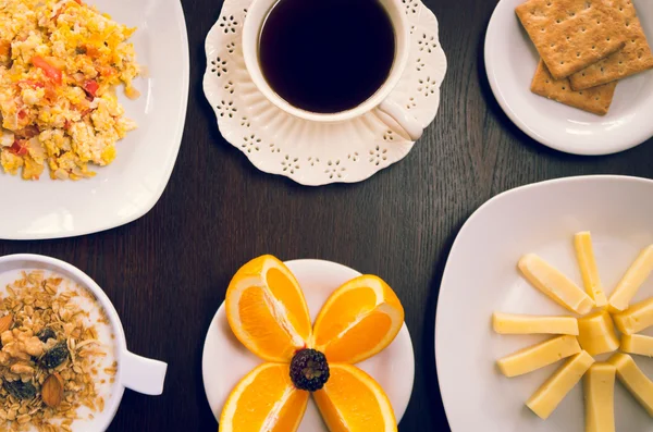 Concept de petit déjeuner élégant vu d'en haut, tasse à café, fromage tranché, oranges, craquelins et bol avec granola de yaourt — Photo