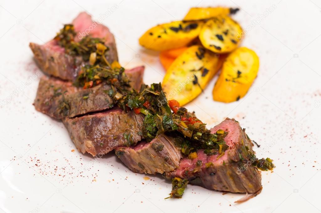 Delicious medallions of tenderloin steak placed upon white dinner plate with some vegetables