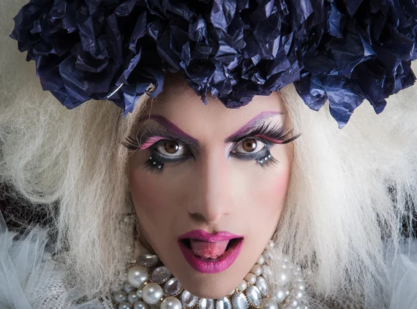 Drag queen wearing spectacular makeup, glamorous trashy look, posing with tongue sticking out of mouth Stock Picture