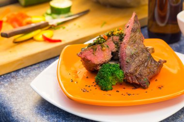 Lezzetli orta nadir sığır filetosu biftek ve sebze turuncu tabağında, zarif sunum yerleştirilir