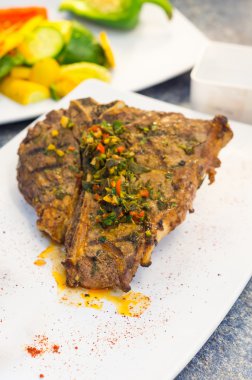 Güzel pişmiş pirzola chimichurri tepesi ile beyaz tabak, zarif sunum yerleştirilen.