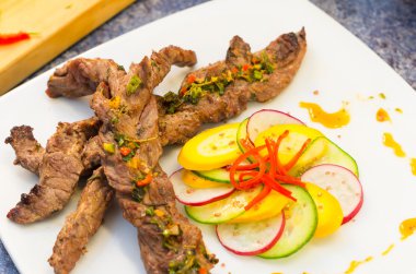 Beyaz tabağında, zarif sunum yerleştirilen sebze ile lezzetli bükülmüş sığır filetosu kesim