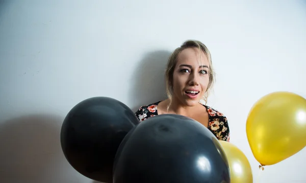 Schönes Modell lehnt sich an weiße Wand zurück und lugt Kopf aus Luftballons — Stockfoto