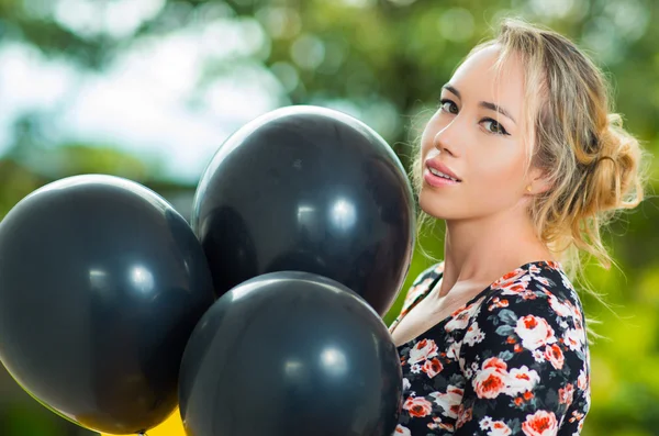 Hermosa modelo hispana con vestido de verano posando para la cámara con globos negros, ángulo de perfil — Foto de Stock