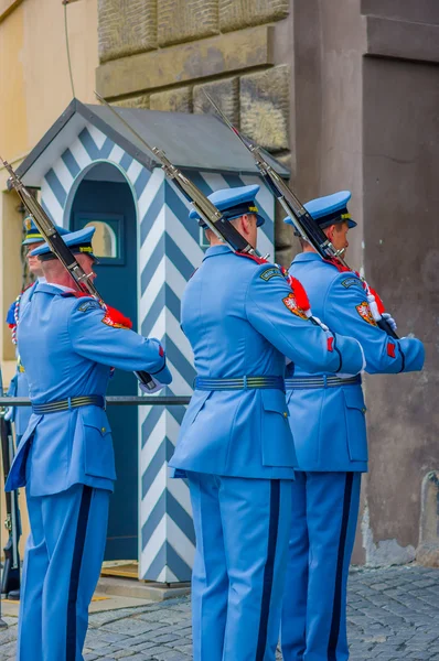 Praga, República Checa - 13 de agosto de 2015: guardas do palácio de plantão vestindo seus uniformes azuis distintivos, cabine listrada branca e arma visível — Fotografia de Stock