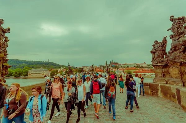 Prague, Czech Republic - 13 August, 2015: People crossing over famous Charles Bridge, statues visible alongside — Stock Fotó