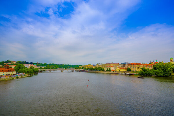 Prague, Czech Republic - 13 August, 2015: Vltava river as seen from Charles Bridge with peacful city sorrounding it, beautiful blue sky