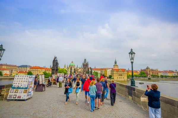 Prague, Czech Republic - 13 August, 2015: People crossing over famous Charles Bridge, statues visible alongside — Stockfoto