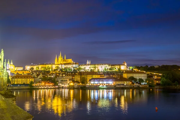 Prague, Czech Republic - 13 August, 2015: Waterfront view of Prague with beautiful lights shining reflective across water, evening sky — Stockfoto