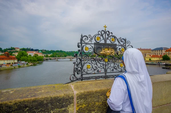 Prag, Tjeckien - 13 augusti 2015: Karlsbron och en av dess många berömda konstinstallationer, en nunna att röra den, river bakgrund — Stockfoto