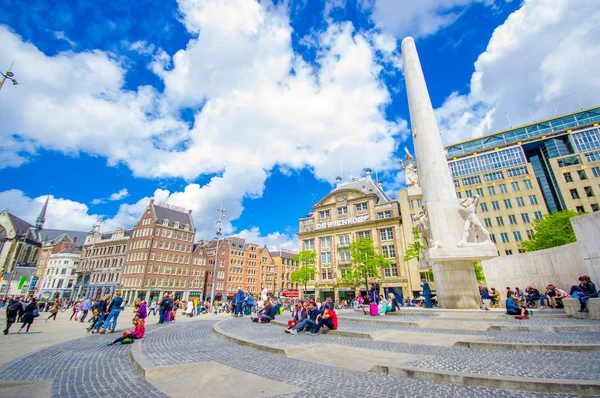 Amsterdam, Nederländerna - 10 juli 2015: Dam-torget på en vacker solig dag, höga monument och historiska byggnader runt plaza — Stockfoto