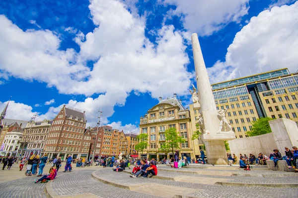 Amsterdam, Nederländerna - 10 juli 2015: Dam-torget på en vacker solig dag, höga monument och historiska byggnader runt plaza — Stockfoto
