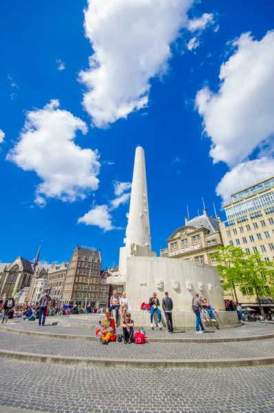 Ámsterdam, Países Bajos - 10 de julio de 2015: Plaza Dam en un hermoso día soleado, alto monumento y edificios históricos alrededor de la plaza — Foto de Stock