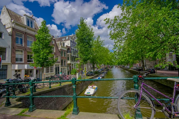 Amsterdam, Paesi Bassi - 10 luglio 2015: Canale dell'acqua visto da un piccolo ponte, alberi verdi ed edifici residenziali accanto — Foto Stock