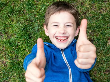 Boy lies on the grass and laughs