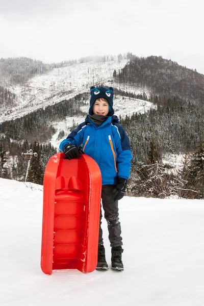 Un ragazzo con la slitta in montagna — Foto Stock