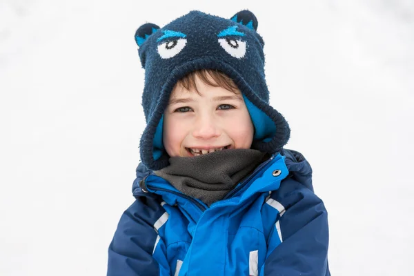 Sebuah potret seorang anak dalam kain musim dingin hangat di latar belakang bersalju Stok Gambar Bebas Royalti