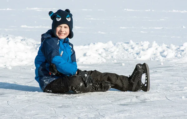 Хлопчик у ковзанах сидить на землі — стокове фото