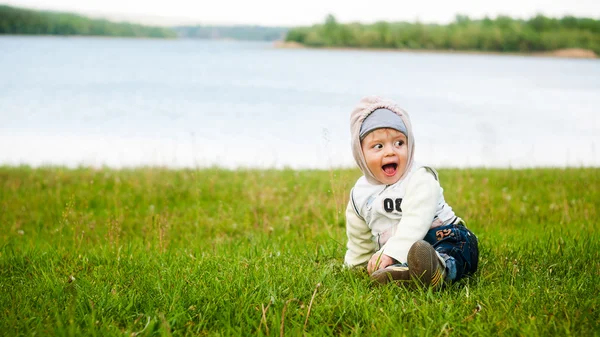 El bebé jugando en la hierba en el río — Foto de Stock