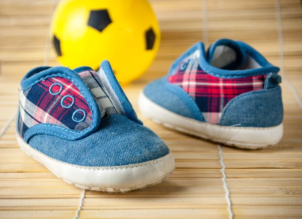 Çocuk spor ayakkabı ve futbol topu bir ahşap zemin üzerinde. Üstten Görünüm — Stok fotoğraf