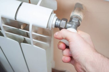 Erkek eli radyatör bataryasını açar. .