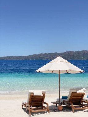 Deniz kenarındaki kumsalda güneşlenmek için yataklar var.