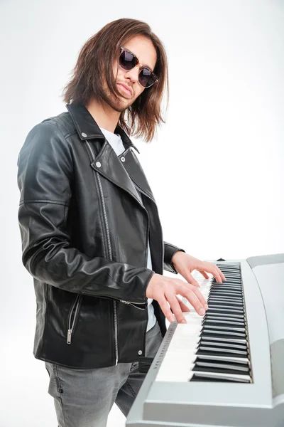 Confident young keyboardist in sunglasses standing and playing on synthesizer — Stock Photo, Image