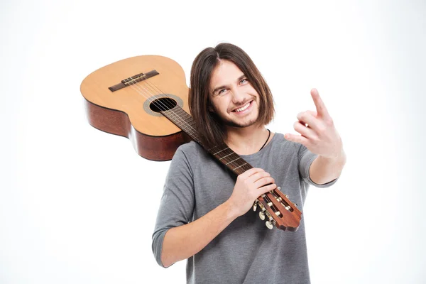 Веселий молодий чоловік тримає гітару і робить рок жест — стокове фото