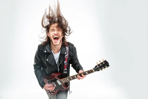 Захоплений молодий чоловік з електричною гітарою кричить і трясе головою — стокове фото
