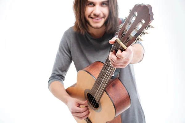 Attractive smiling young man with long hair playing acoustic guitar — Stock Photo, Image