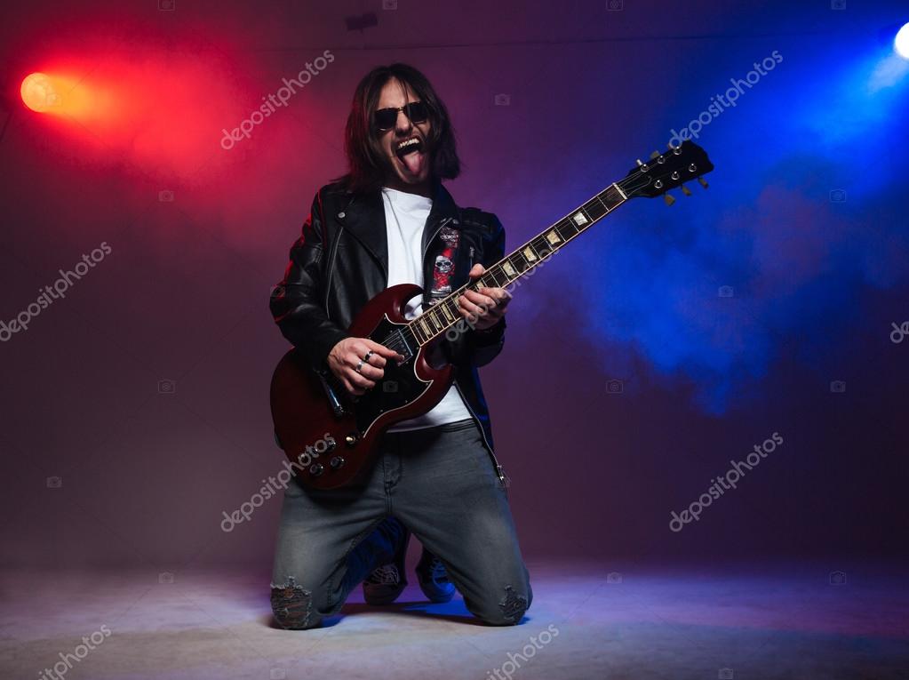 Crazy young guitarist playing electric guitar and shoing tongue Stock